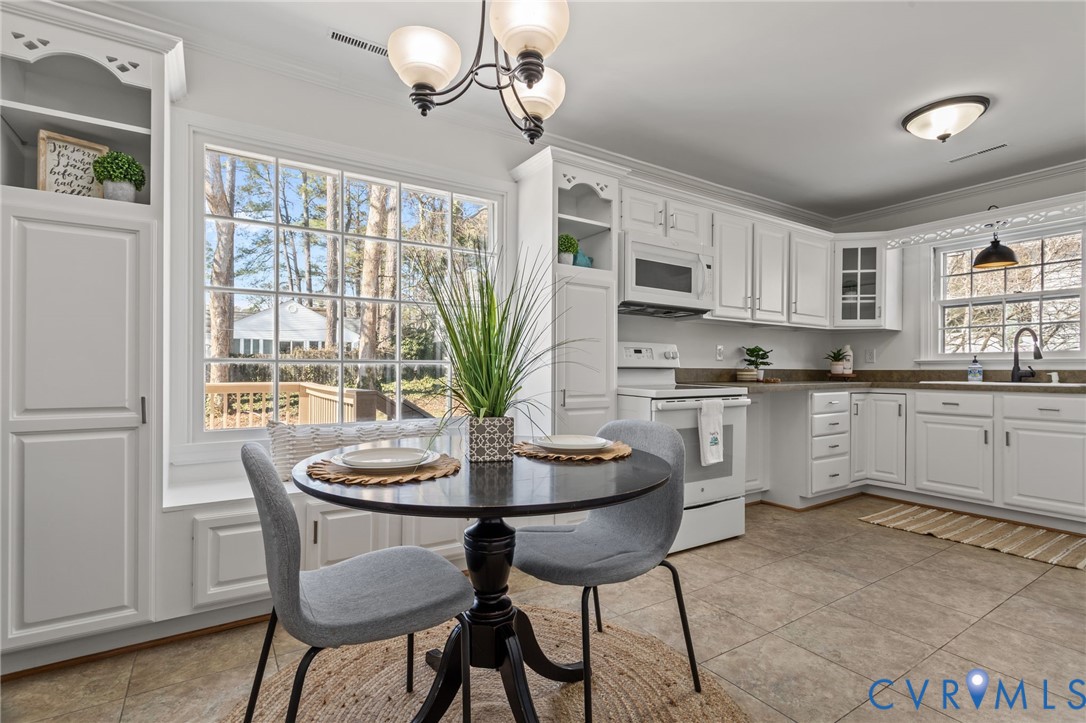 1316 Ware Road Henrico, VA 23229 - Photo 17 of 51 a kitchen with a dining table chairs and white cabinets