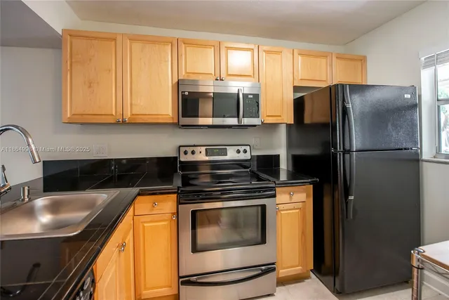 a kitchen with stainless steel appliances granite countertop a refrigerator a stove a sink and a microwave