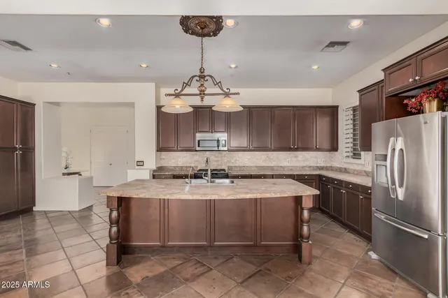 a kitchen with stainless steel appliances granite countertop a sink a stove a refrigerator cabinets and chairs