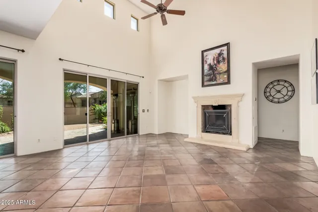 a view of a livingroom with a fireplace a ceiling fan and wooden floor