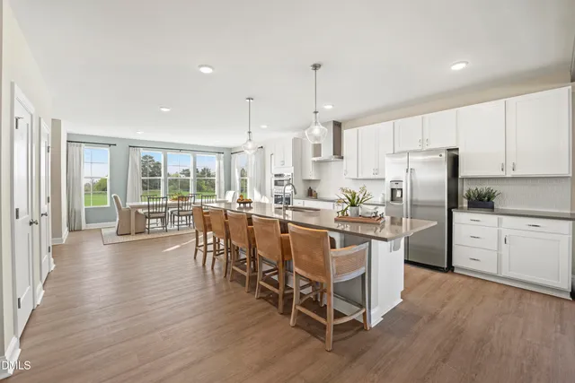 a kitchen with stainless steel appliances a dining table chairs stove a refrigerator and cabinets