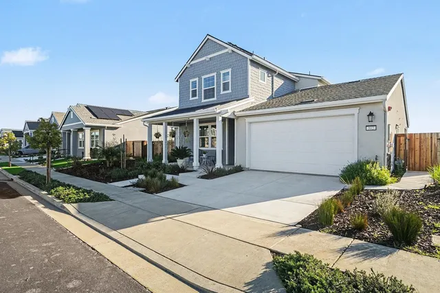 a front view of a house with a yard and potted plants