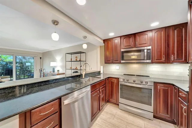 a kitchen with stainless steel appliances granite countertop wooden cabinets a sink and a stove