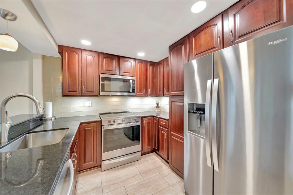 3000 Northeast 5th Terrace, Unit 109A Wilton Manors, FL 33334 - Photo 21 of 36 a kitchen with stainless steel appliances granite countertop a refrigerator stove and sink