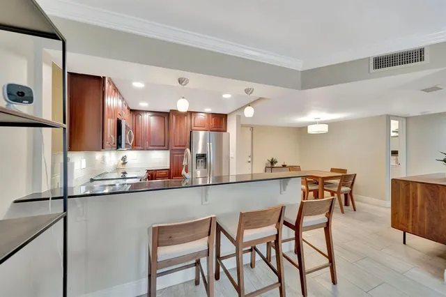a kitchen with stainless steel appliances kitchen island granite countertop a table chairs sink and cabinets