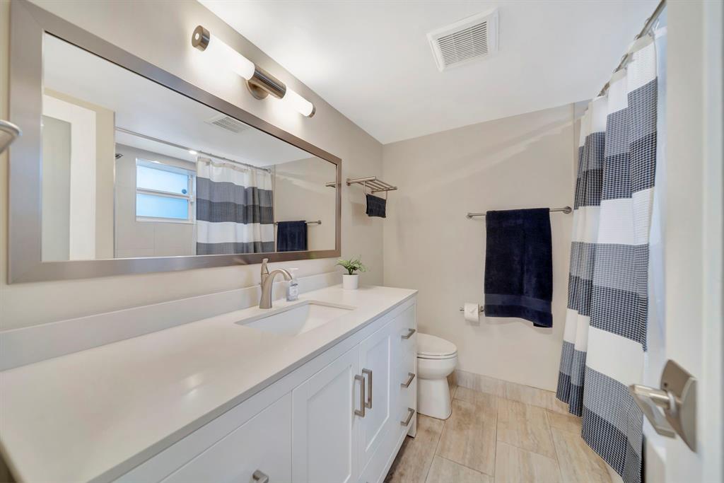 3000 Northeast 5th Terrace, Unit 109A Wilton Manors, FL 33334 - Photo 10 of 36 a spacious bathroom with a double vanity sink toilet and shower