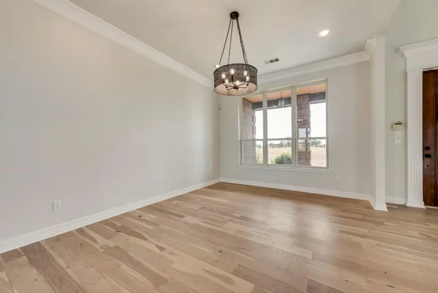 a view of an empty room with wooden floor and windows