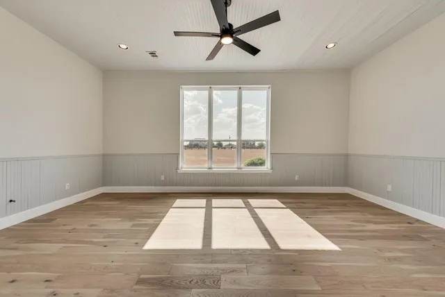 a view of empty room with wooden floor and fan