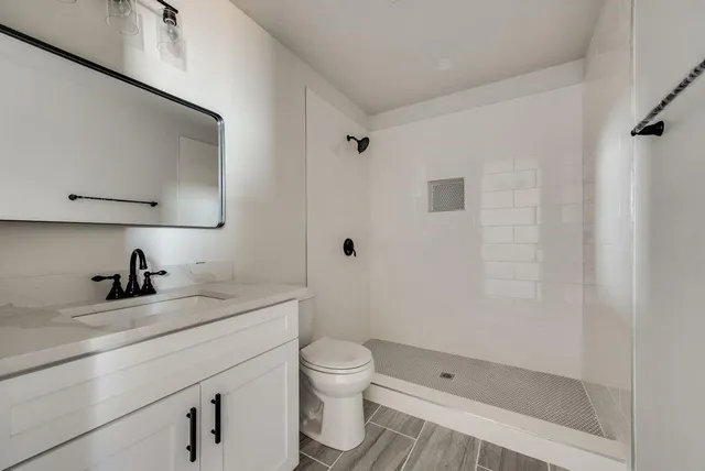 a bathroom with a granite countertop sink a toilet and a shower