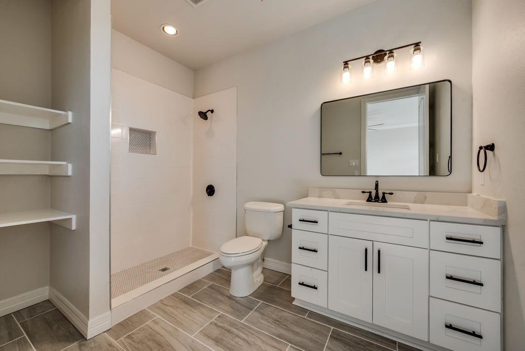 3330 Greathouse Road Waxahachie, TX 75167 - Photo 31 of 40 a bathroom with a toilet a sink a mirror and a shower