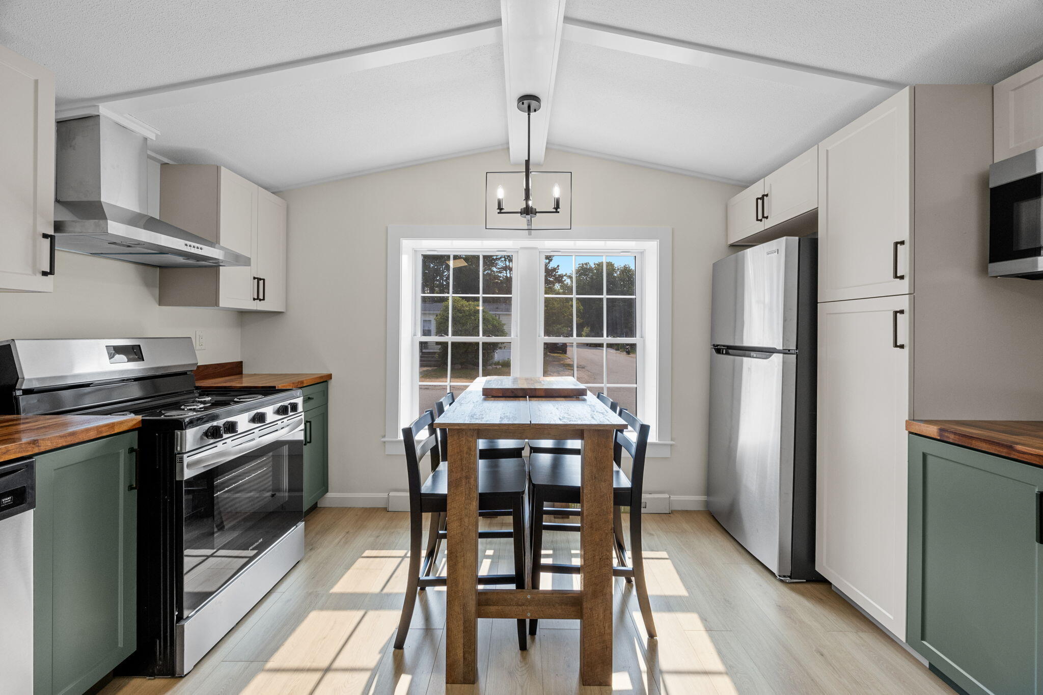 15 1st Street Bourne, MA 02559 - Photo 11 of 30 a kitchen with stainless steel appliances a dining table chairs stove and refrigerator