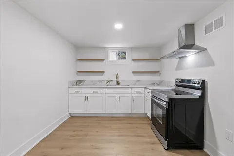 a kitchen with white cabinets stainless steel appliances and wooden floor