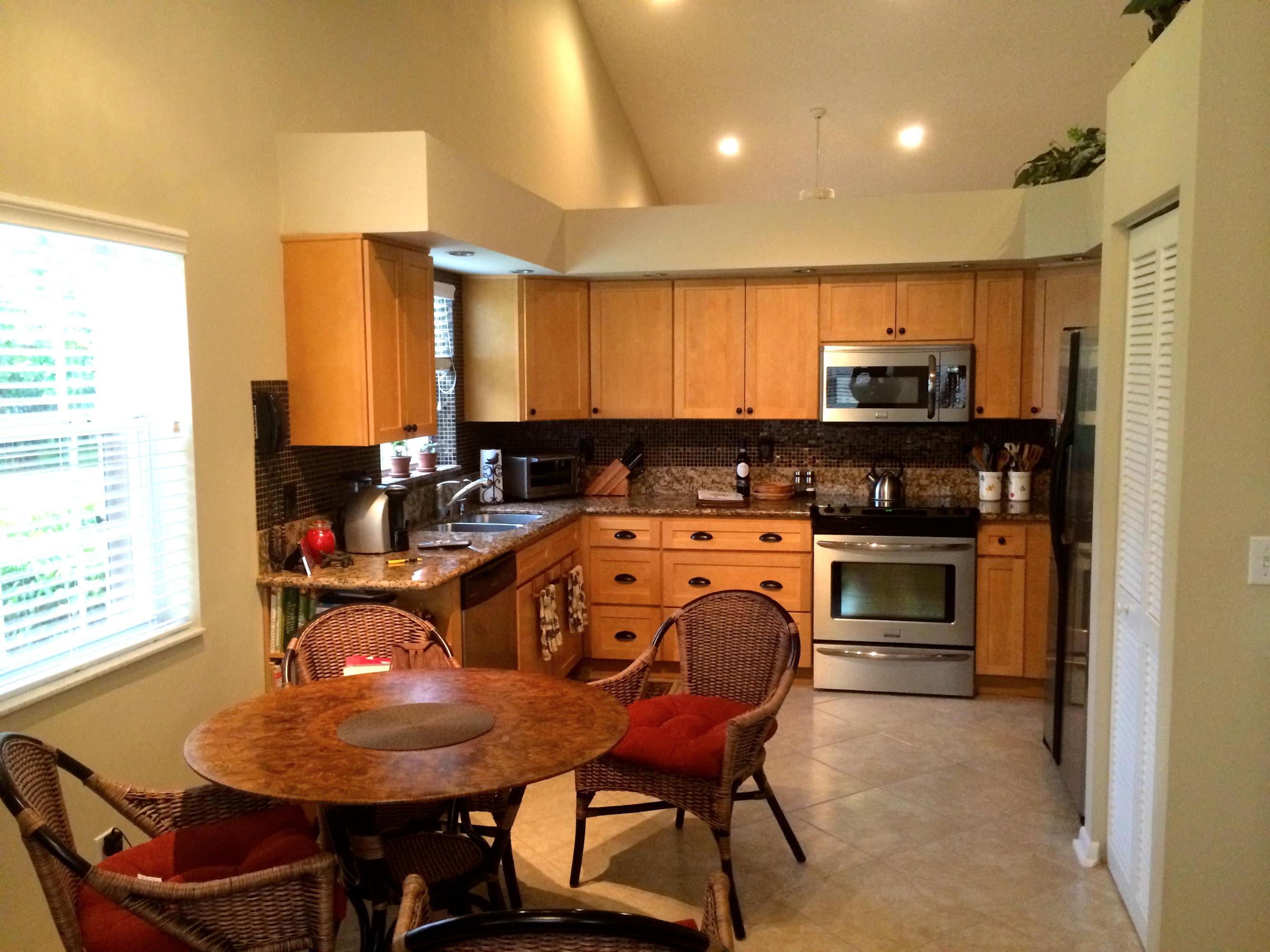 7540 Diamond Pointe Circle Delray Beach, FL 33446 - Photo 2 of 18 a kitchen with kitchen island a stove a table and chairs in it