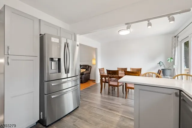 a room with stainless steel appliances a refrigerator and a table chair