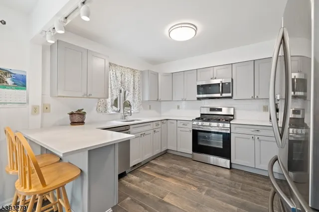 a kitchen with stainless steel appliances granite countertop a stove a sink dishwasher a refrigerator a microwave oven with cabinets and wooden floor