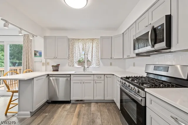 a kitchen with stainless steel appliances a sink cabinets and a window