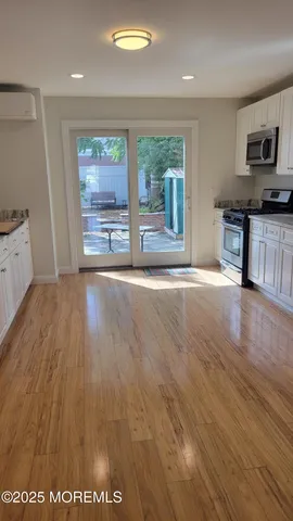 a view of an empty room with a window and wooden floor