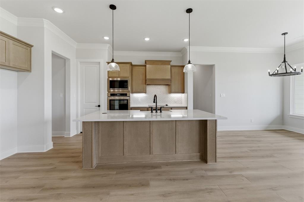 2204 Continent Court Krum, TX 76249 - Photo 16 of 28 Kitchen featuring a large central island with a light-toned countertop, wood-finish flooring, recessed lighting, and pendant fixtures