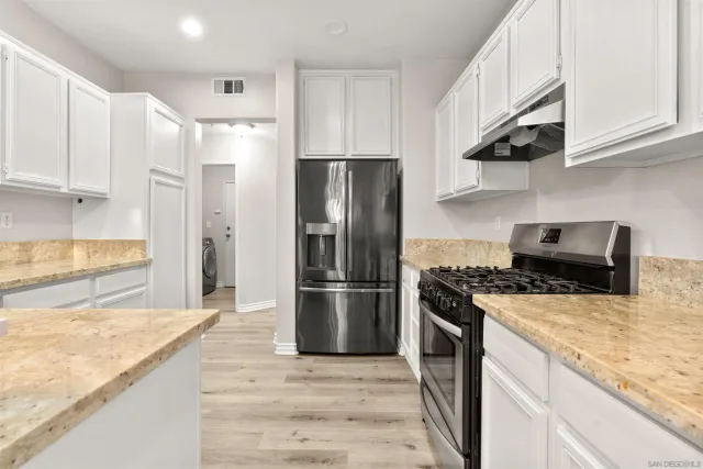 a kitchen with stainless steel appliances granite countertop a stove a refrigerator and a sink