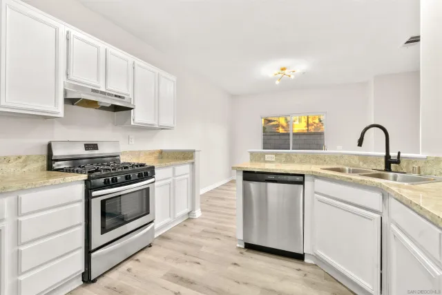 a kitchen with stainless steel appliances granite countertop a stove a sink and a microwave
