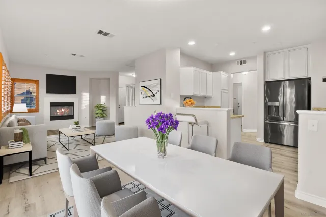 a living room with stainless steel appliances furniture a dining table and a fireplace