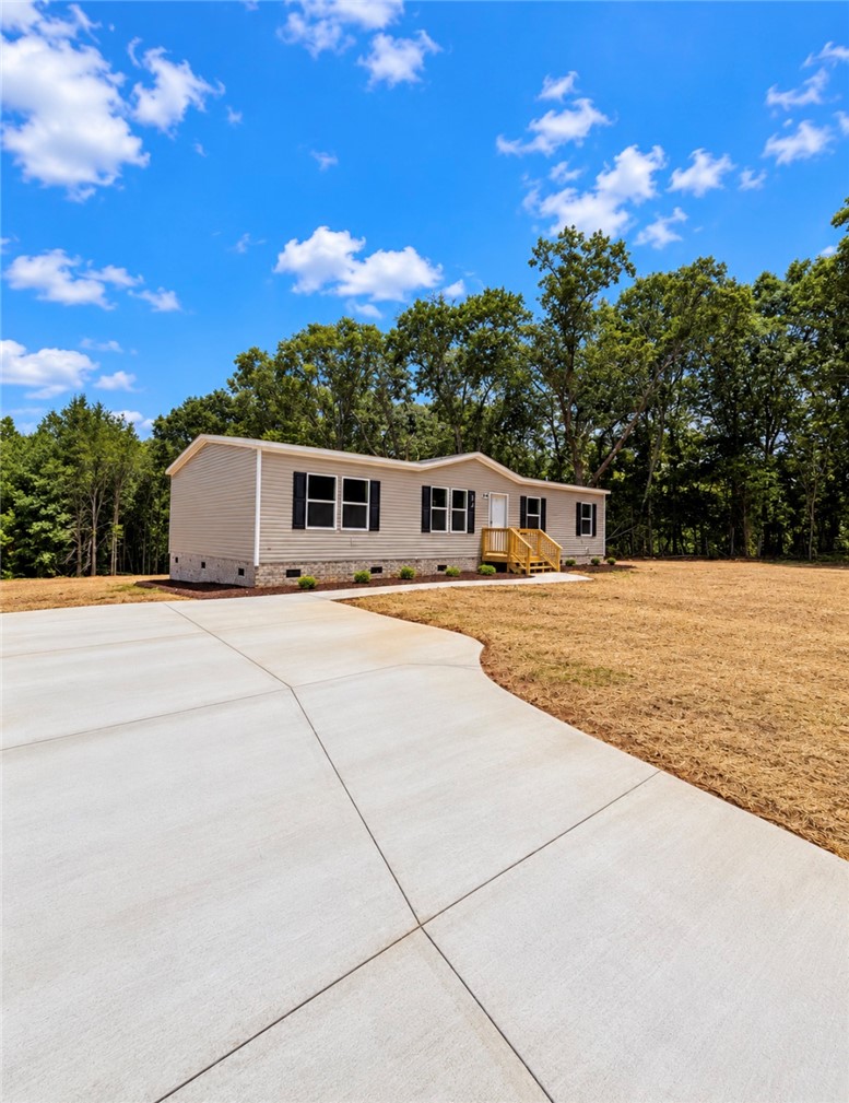 1411 Slaton Road Townville, SC 29689 - Photo 2 of 17 A spacious concrete driveway leads toward this classic home bordered by mature trees.