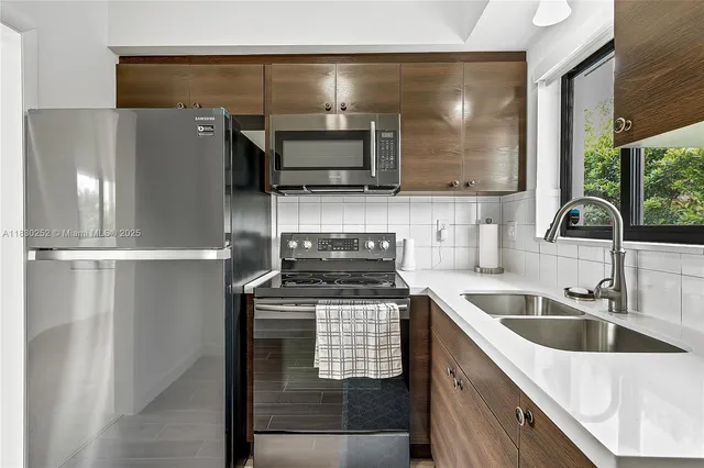 a kitchen with stainless steel appliances granite countertop a sink a stove and a refrigerator