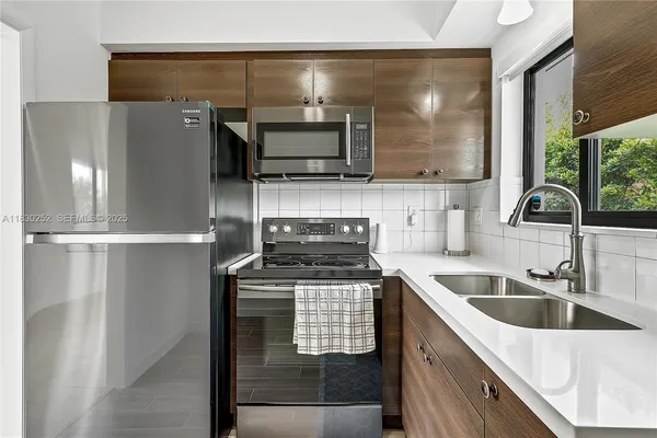 a kitchen with stainless steel appliances granite countertop a sink a stove and a refrigerator
