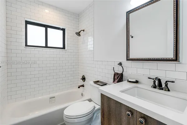 a bathroom with a sink a toilet a mirror a vanity and bathtub