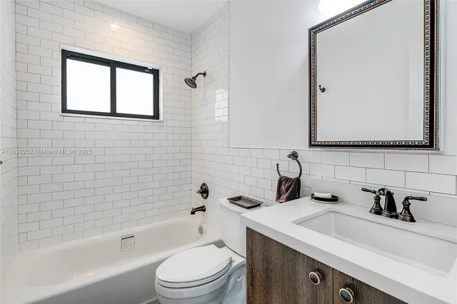 a bathroom with a sink a toilet a mirror a vanity and bathtub