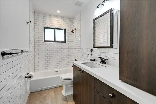 a bathroom with a sink a toilet a mirror and bathtub