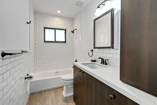 a bathroom with a sink a toilet a mirror and bathtub