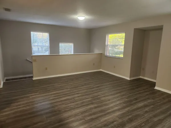 an empty room with wooden floor and windows