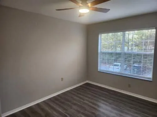 an empty room with wooden floor and windows
