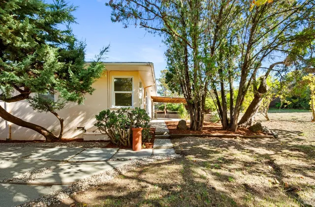 a view of a house with a big yard and large trees