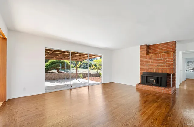 a view of an empty room with wooden floor and a fireplace
