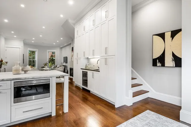 a kitchen with kitchen island sink stove and white cabinets with wooden floor