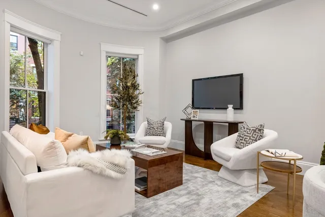 a living room with furniture a flat screen tv and a window