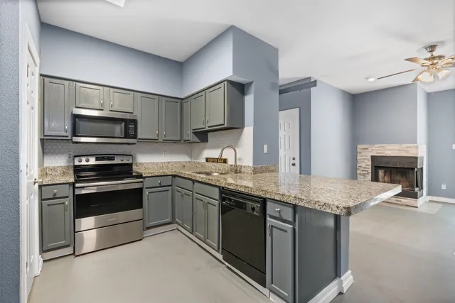a kitchen with stainless steel appliances granite countertop a stove top oven a sink and a microwave
