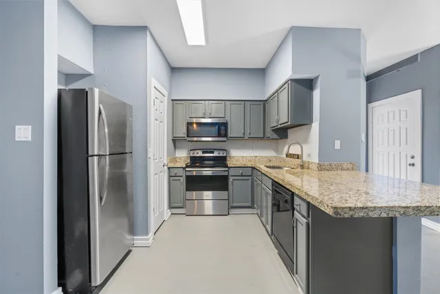 a kitchen with stainless steel appliances granite countertop a refrigerator a stove and a sink