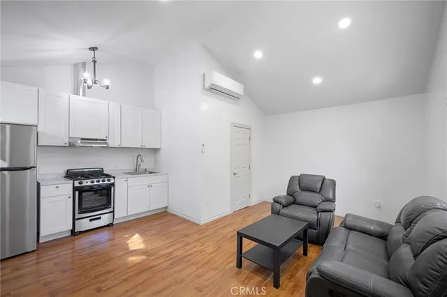 a living room with stainless steel appliances furniture and wooden floor