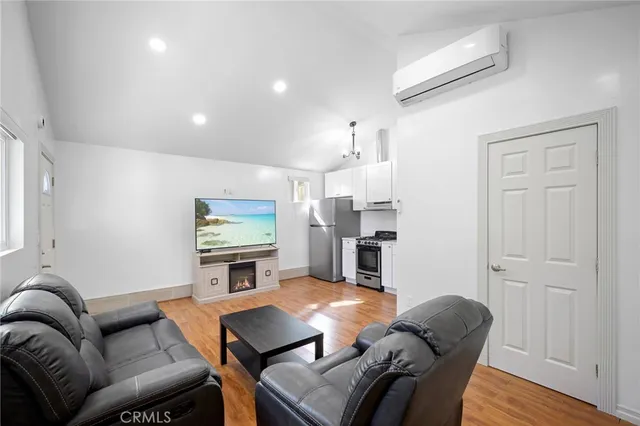 a living room with furniture a flat screen tv and kitchen view