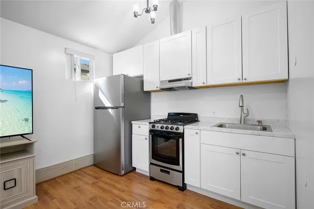 a kitchen with stainless steel appliances granite countertop a refrigerator sink and white cabinets