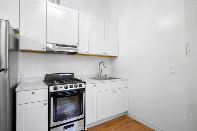 a kitchen with stainless steel appliances granite countertop a stove a sink and white cabinets