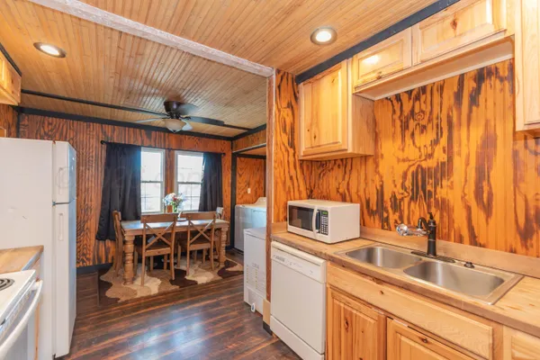 a kitchen with stainless steel appliances granite countertop a sink dishwasher and a refrigerator with wooden floor