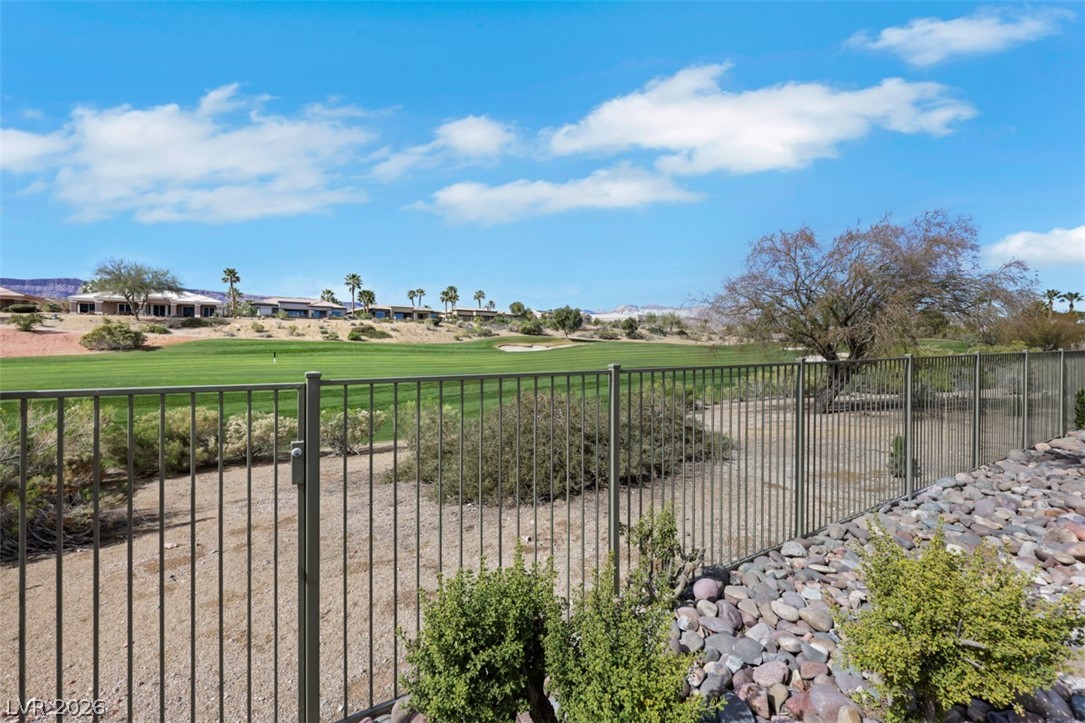 5015 Rivedro Street Las Vegas, NV 89135 - Photo 9 of 91 A golf course property with a fence, showcasing lush greens and desert landscaping.