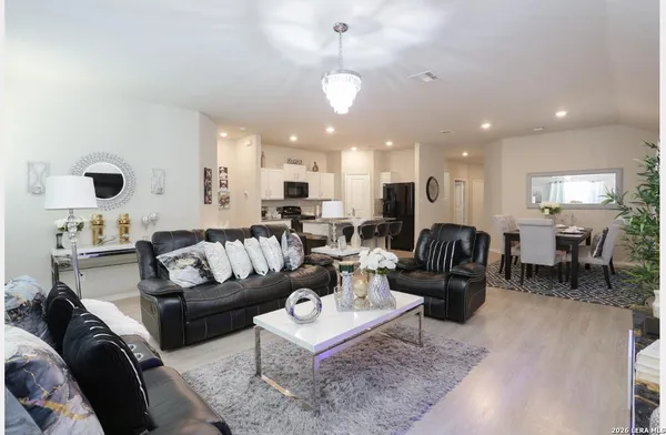 a living room with furniture kitchen view and a chandelier
