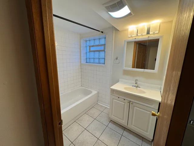 a bathroom with a tub sink and mirror