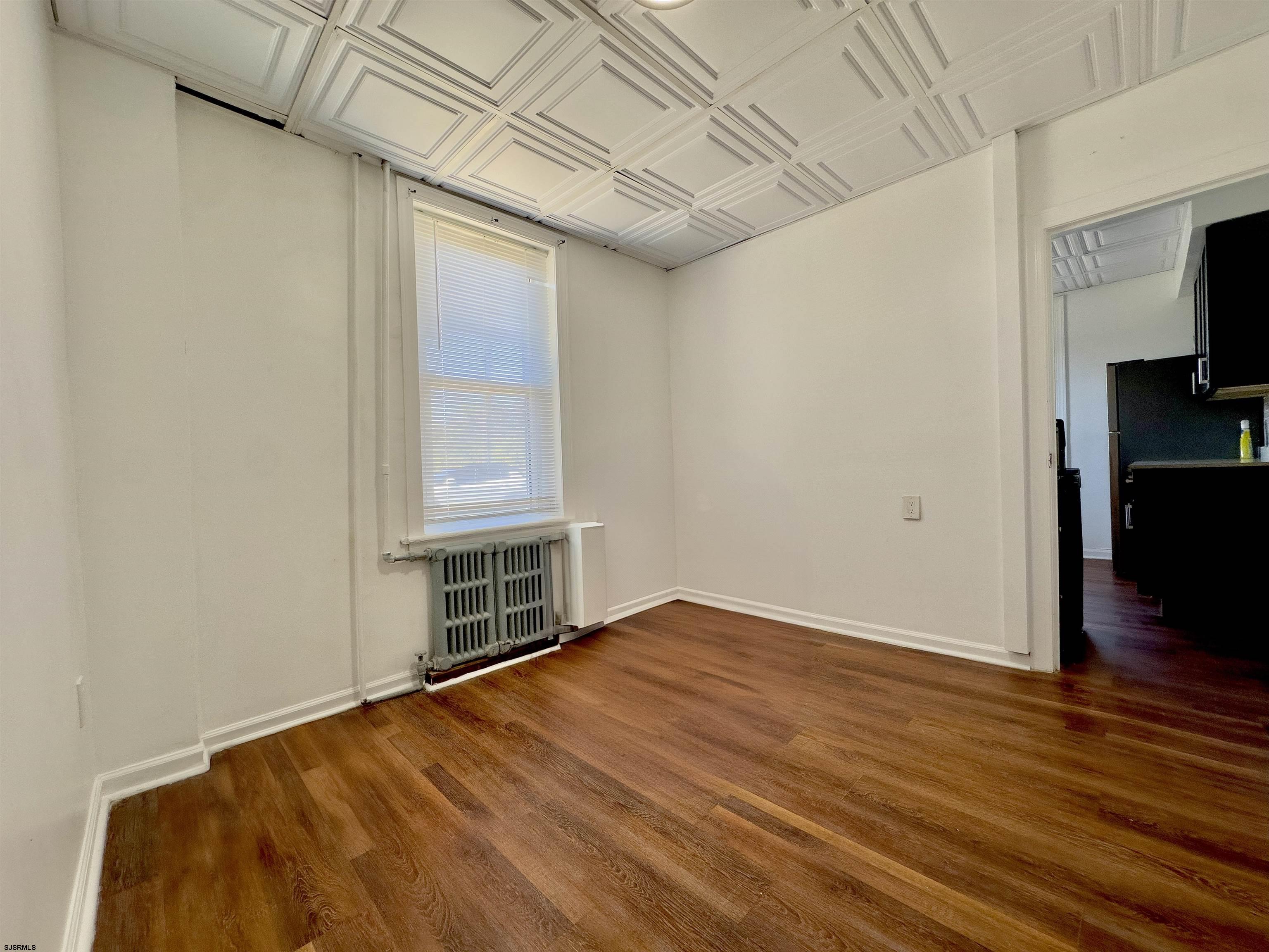 101 New Jersey Avenue, Unit A Atlantic City, NJ 08401 - Photo 5 of 13 a view of an empty room with wooden floor and a window