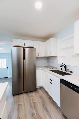 a kitchen with stainless steel appliances granite countertop a refrigerator a sink and white cabinets